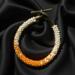 Handmade Orange Creamsicle Kumihimo bracelet featuring orange and ivory glass seed beads with brass toggle clasp on black satin fabric